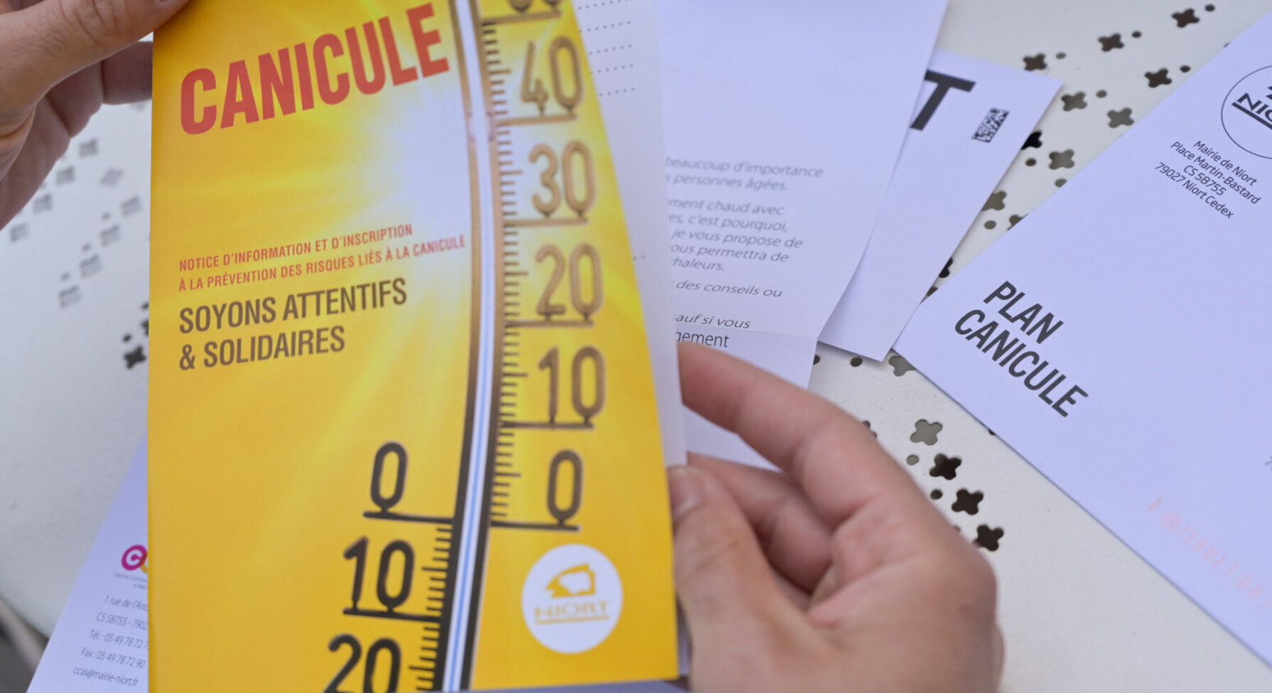 Brochure Plan Canicule de la Ville de Niort tenue en main, avec thermomètre et slogan « Soyons attentifs & solidaires »